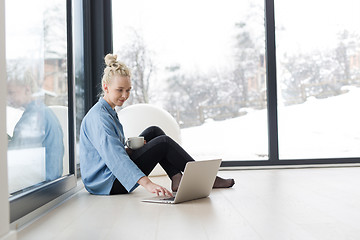 Image showing woman drinking coffee and using laptop at home