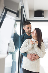 Image showing multiethnic couple enjoying morning coffee by the window