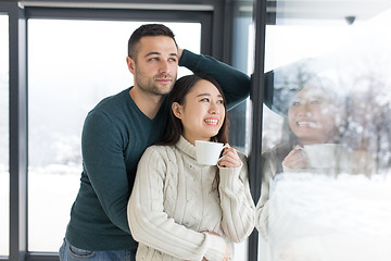 Image showing multiethnic couple enjoying morning coffee by the window