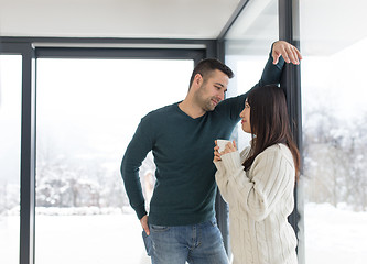 Image showing multiethnic couple enjoying morning coffee by the window