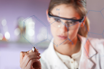 Image showing Portrait of a confident female researcher in life science laboratory writing structural chemical formula on a glass board.