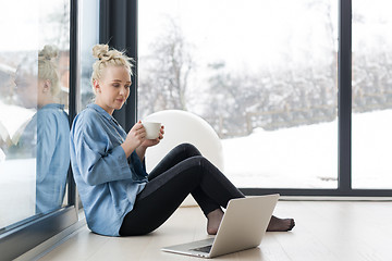 Image showing woman drinking coffee and using laptop at home