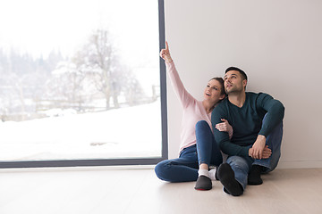 Image showing young couple sitting on the floor near window at home