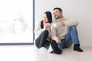 Image showing multiethnic couple enjoying morning coffee by the window