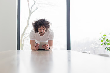 Image showing young man using a tablet at home