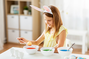 Image showing girl coloring easter eggs by liquid dye at home