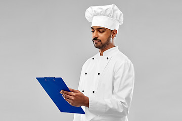 Image showing male indian chef reading menu on clipboard