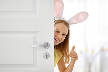 Image showing happy girl with easter bunny ears peeking out door