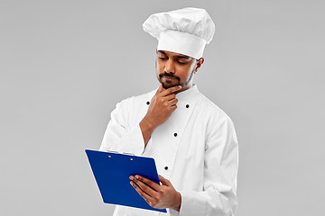 Image showing male indian chef reading menu on clipboard