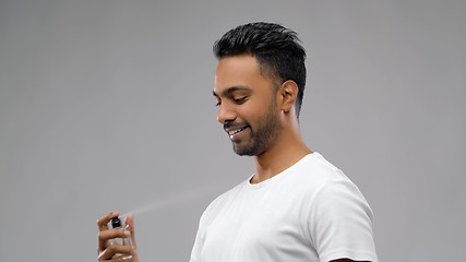 Image showing happy indian man with perfume over grey background