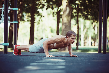 Image showing Athlete doing exercises at stadium at park