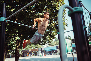 Image showing Athlete doing exercises at stadium at park