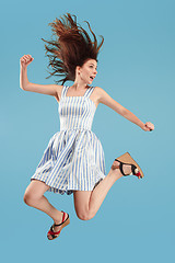 Image showing Freedom in moving. Pretty young woman jumping against blue background