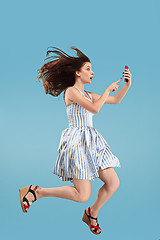 Image showing Full length of pretty young woman with mobile phone while jumping