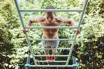 Image showing Athlete doing exercises at stadium at park