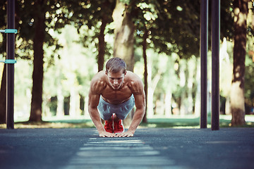 Image showing Athlete doing exercises at stadium at park