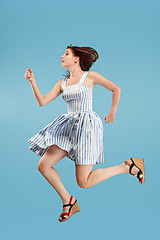 Image showing Freedom in moving. Pretty young woman jumping against blue background