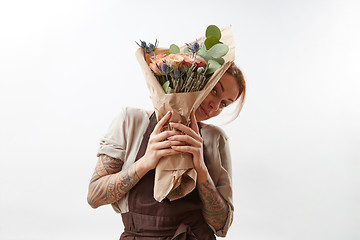 Image showing Smiling girl holds greeting bunch from fragrant beautiful flowers living coral colored on a gray background. Copy space. Concept Mother\'s Day.