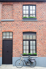 Image showing Bruges, Belgium - August 16, 2013: View of the wall with windows, dark door and vintage bike with bag