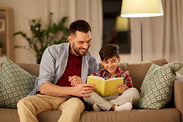 Image showing happy father and son reading book sofa at home