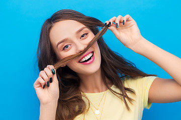 Image showing happy young woman making mustache with her hair