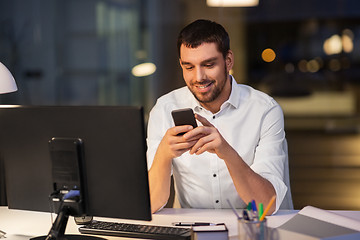 Image showing businessman with smartphone and computer at office