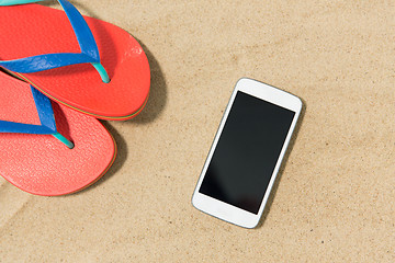 Image showing smartphone and flip flops on beach sand