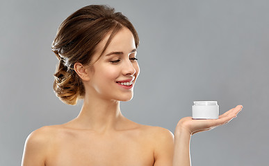 Image showing happy young woman holding jar of cream