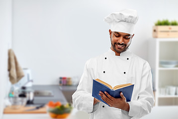 Image showing happy male indian chef reading cookbook at kitchen