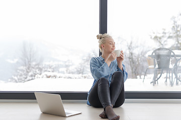 Image showing woman drinking coffee and using laptop at home