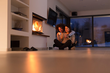 Image showing happy multiethnic couple sitting in front of fireplace