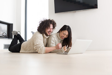 Image showing young multiethnic couple using a laptop on the floor