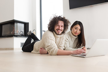 Image showing young multiethnic couple using a laptop on the floor