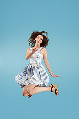 Image showing Freedom in moving. Pretty young woman jumping against blue background