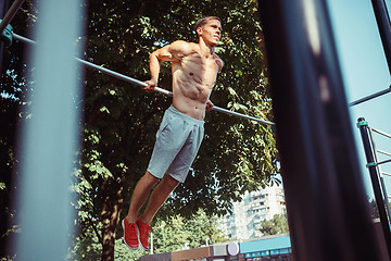 Image showing Athlete doing exercises at stadium at park