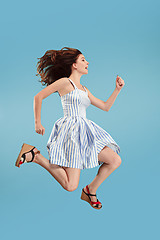 Image showing Freedom in moving. Pretty young woman jumping against blue background