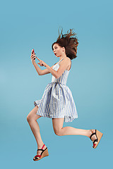 Image showing Full length of pretty young woman with mobile phone while jumping