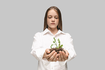 Image showing Teen hands with seedlings on gray studio background. Spring concept, nature and care.