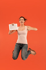 Image showing Image of young woman over blue background using laptop computer or tablet gadget while jumping.