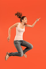 Image showing Freedom in moving. Pretty young woman jumping against orange background