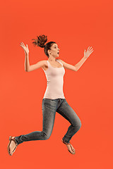 Image showing Freedom in moving. Pretty young woman jumping against orange background