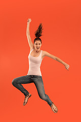 Image showing Freedom in moving. Pretty young woman jumping against orange background