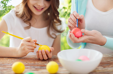 Image showing happy smiling girl and mother coloring easter eggs