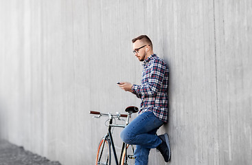 Image showing hipster man in earphones with smartphone and bike