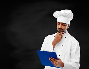 Image showing chef reading menu on clipboard over chalkboard