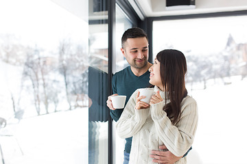 Image showing multiethnic couple enjoying morning coffee by the window