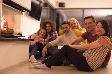 Image showing multiethnic couples sitting in front of fireplace