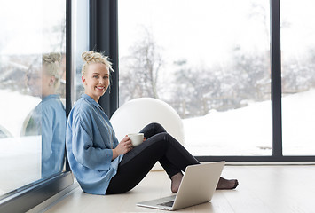 Image showing woman drinking coffee and using laptop at home