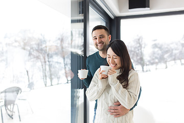 Image showing multiethnic couple enjoying morning coffee by the window