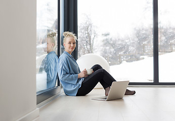 Image showing woman drinking coffee and using laptop at home